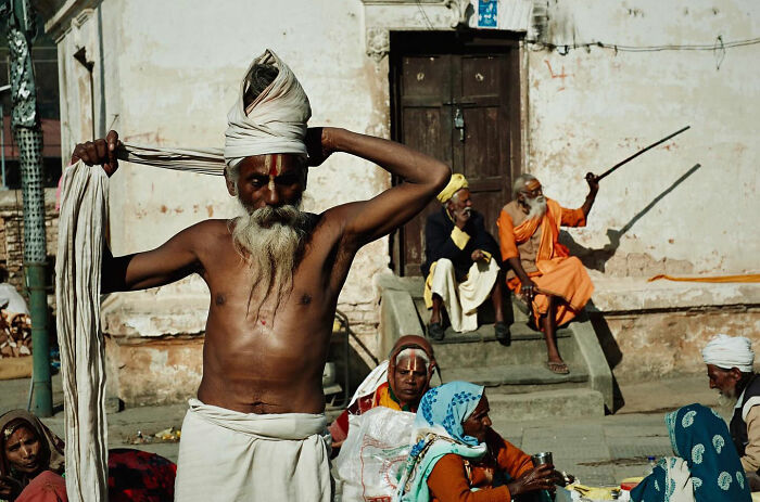 Elderly man with a turban and beard among a group of people in candid everyday moments from Asia.