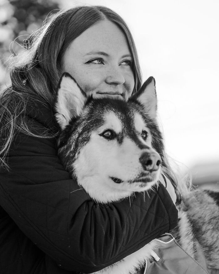 Black and white photo of a couple sharing a tender moment with their dog, capturing touching final moments between pets and humans.