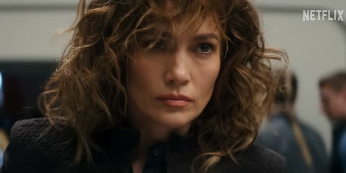 Close-up of a woman with curly hair in a serious expression in a Netflix movie scene about Netflix movies letdowns.