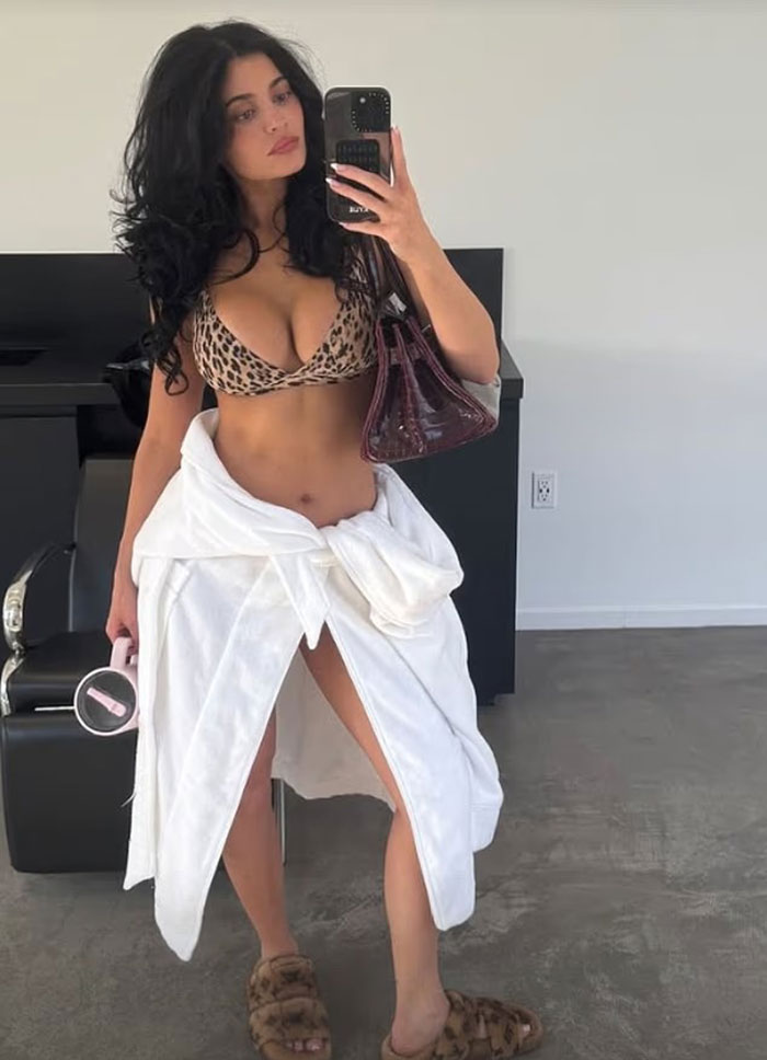 Kylie Jenner rocks risqué leopard print outfit with white robe tied around waist in a casual indoor setting. Kylie Jenner rocks risqué leopard print outfit with white robe tied around waist in a casual indoor setting.