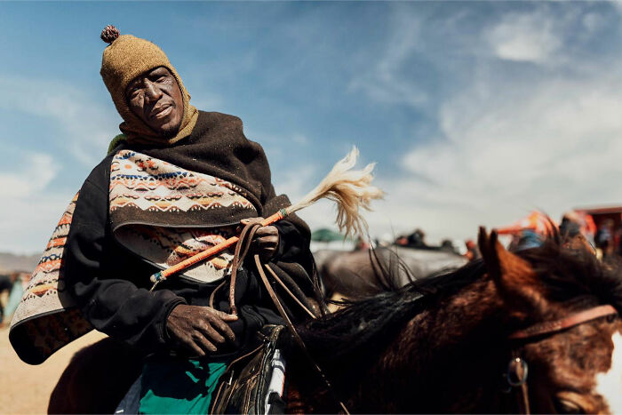 Man wearing traditional clothing riding a horse in a candid everyday moment captured by photographer Gil Kreslavsky.