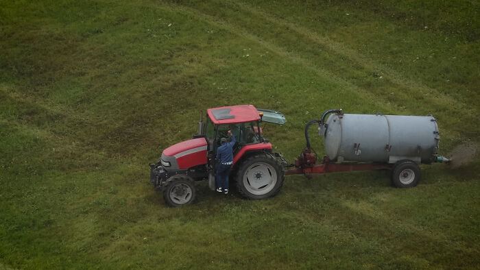 Farmer spraying manure with tractor on green field, capturing viral moment involving squatters from a photographer's viewpoint. Farmer spraying manure with tractor on green field, capturing viral moment involving squatters from a photographer's viewpoint.
