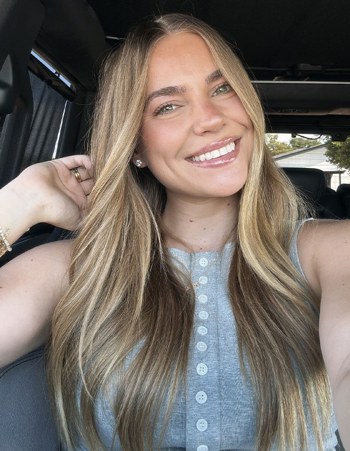 Woman with long blonde hair smiling in a car, related to momfluencer after 3-year-old's tragic drowning in home pool. Woman with long blonde hair smiling in a car, related to momfluencer after 3-year-old's tragic drowning in home pool.