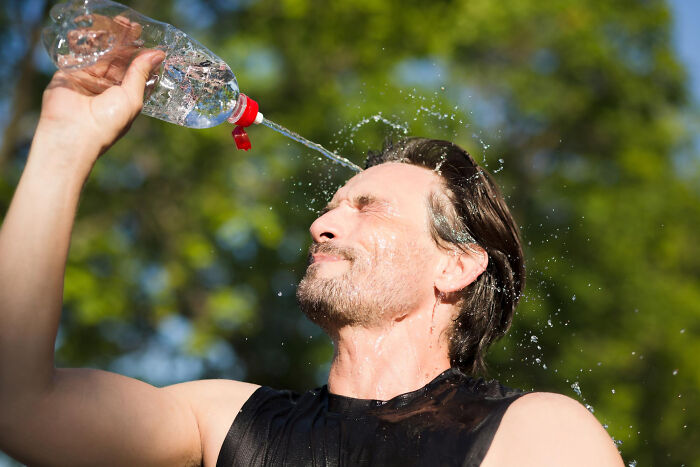Man cooling off with water from a bottle outdoors, illustrating unhinged hacks done to land a job effectively.