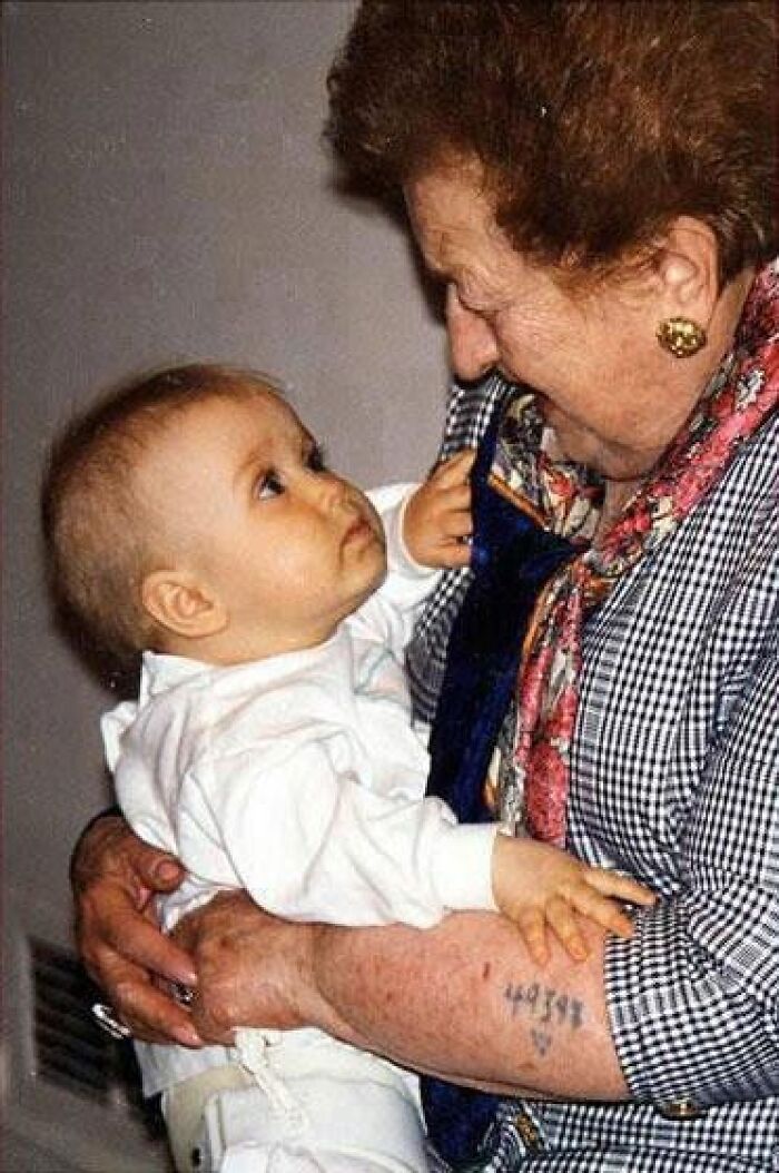 Elderly woman with a tattoo holding a baby, a touching historical photo with an interesting backstory.