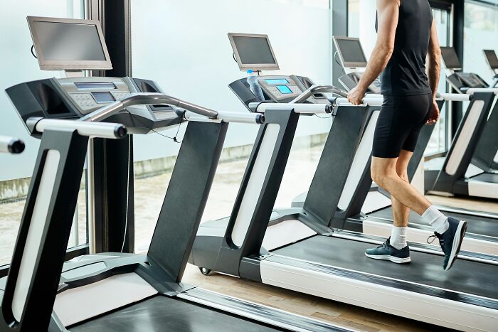 Person walking on a treadmill in a gym, showcasing ingenious inventions that found new purposes over the years.