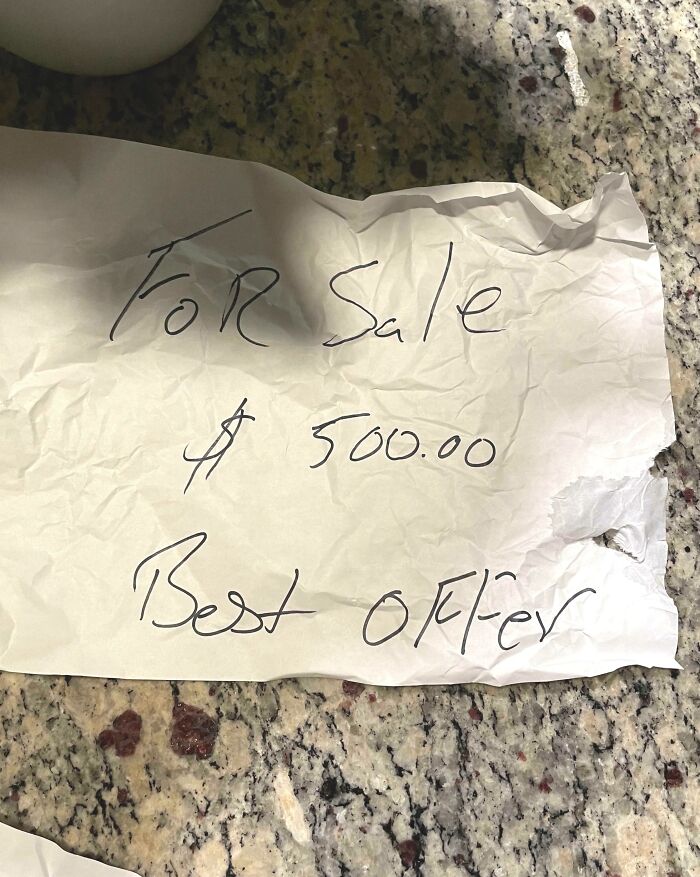 Crumpled handwritten note on granite countertop with unhinged neighbors’ notes humorously offering item for sale.
