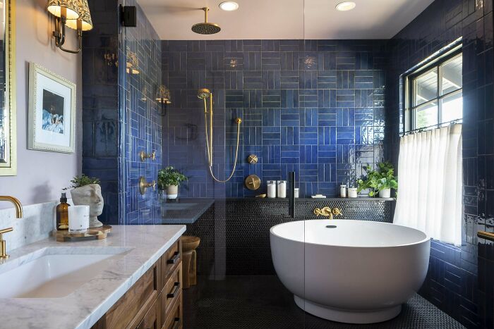 Modern bathroom with bold blue tile walls, freestanding tub, gold fixtures, and stylish home decoration details.