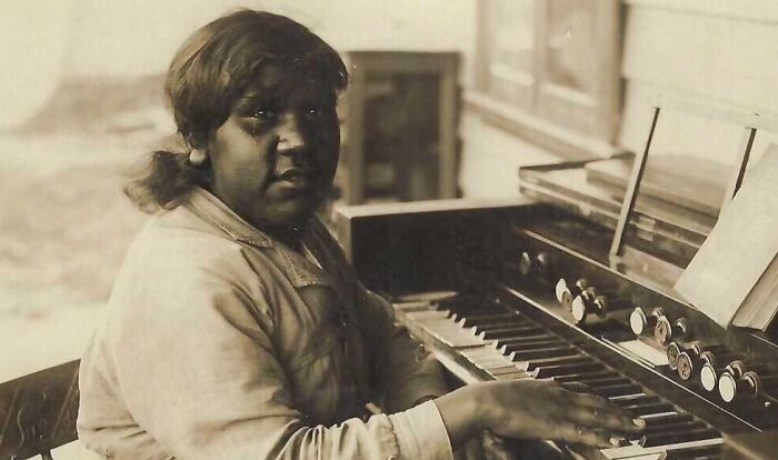 Indigenous Australian woman from the 1900s playing an old organ, offering rare glimpses into history through striking photos.
