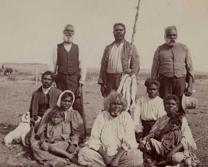 Group of Indigenous Australians in the 1900s, posed outdoors on rural land, capturing rare historical moments.
