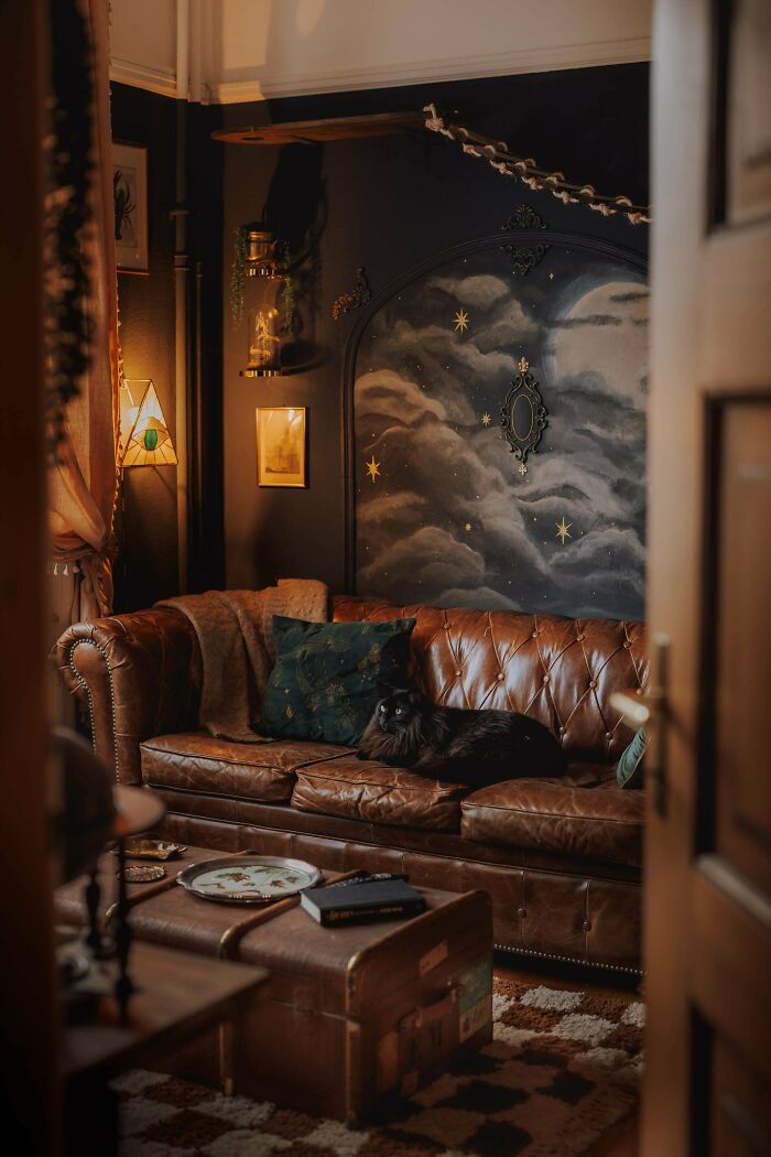Cozy home corner with a leather sofa, celestial wall art, and warm lighting showcasing proud home decorating.