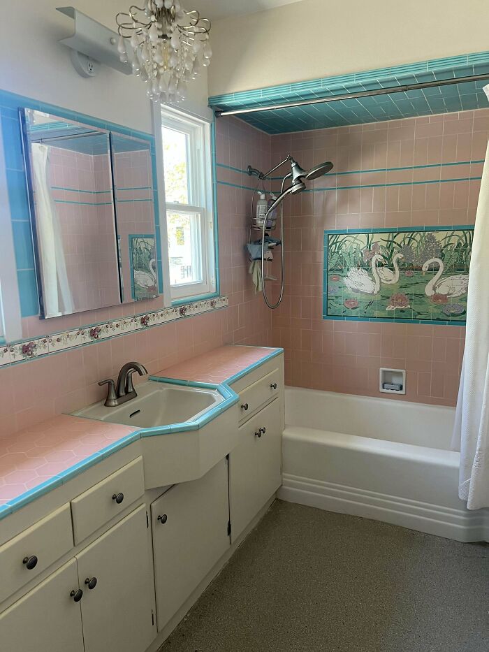 Vintage bathroom corner with pink and turquoise tile decor, featuring a swan mosaic and unique vanity design.