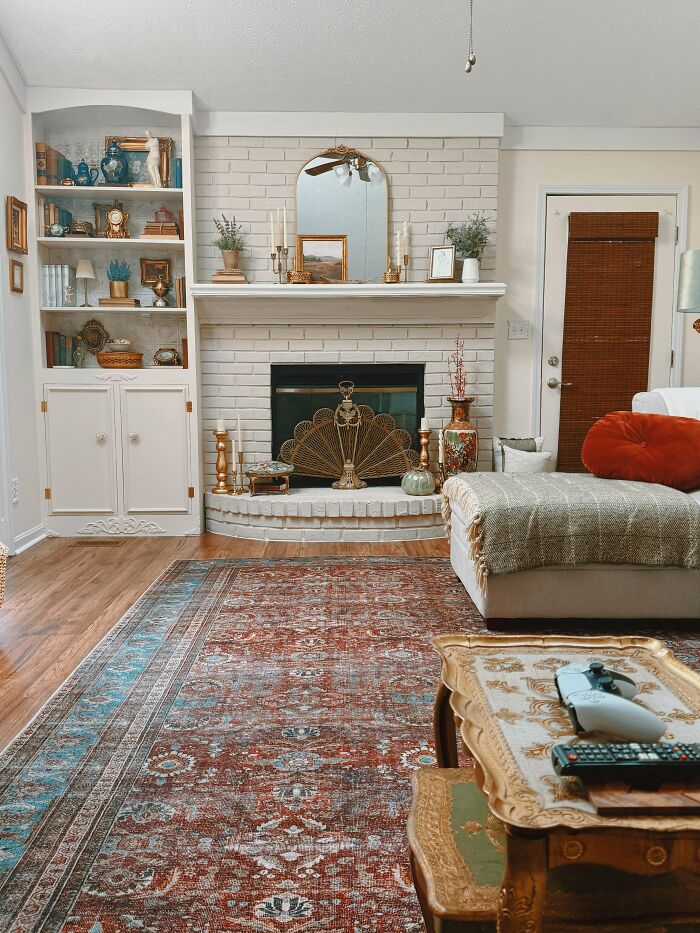 Cozy decorated home corner with a fireplace, bookshelf, antique rug, and comfortable seating showcasing proud decorating choices.