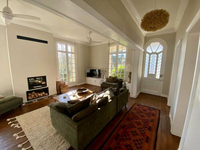 Cozy living room corner with green sofa, natural light, fireplace, and wooden flooring, showcasing home decorating pride.