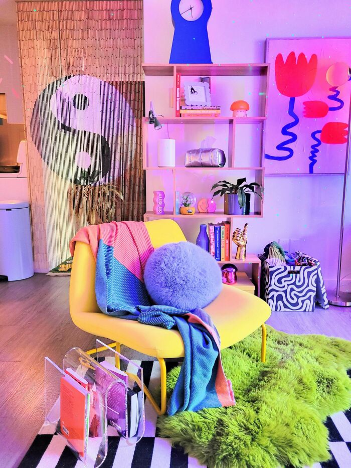 Colorful cozy corner with a yellow chair, textured cushions, bookshelf, and vibrant home decorating accents.