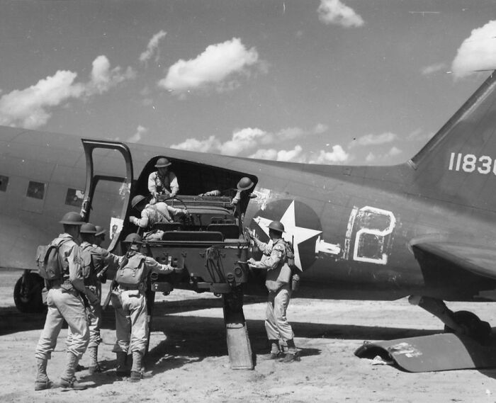 World War II soldiers loading equipment into a military aircraft, rare WWII photo capturing wartime logistics in action.