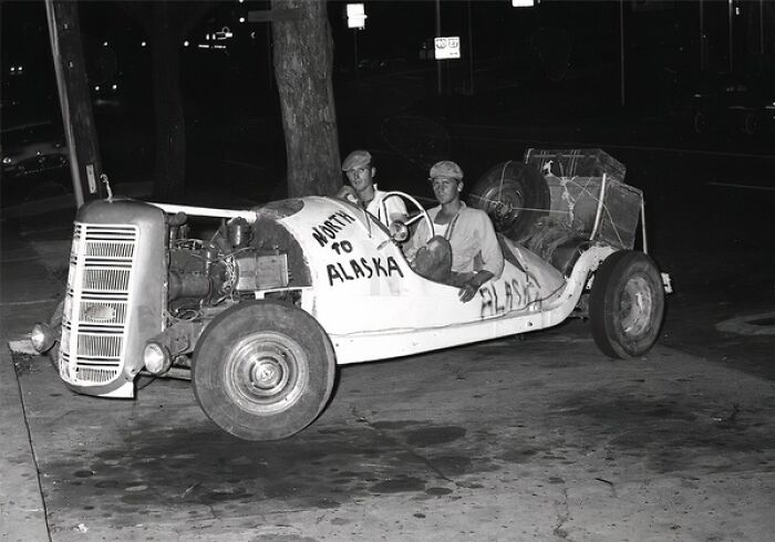 Two men sitting in a vintage car on a street at night, capturing iconic glimpses into everyday life in 1950s Florida.