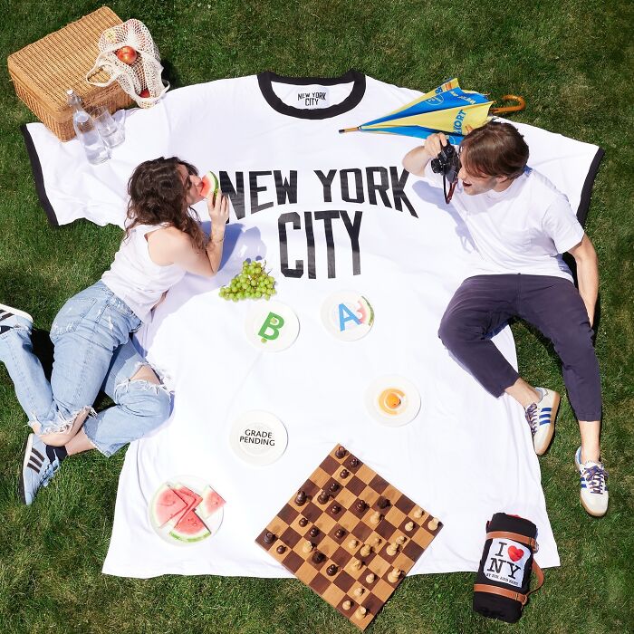 Two people enjoying a picnic on a large fashion accessory blanket blending everyday objects with design.