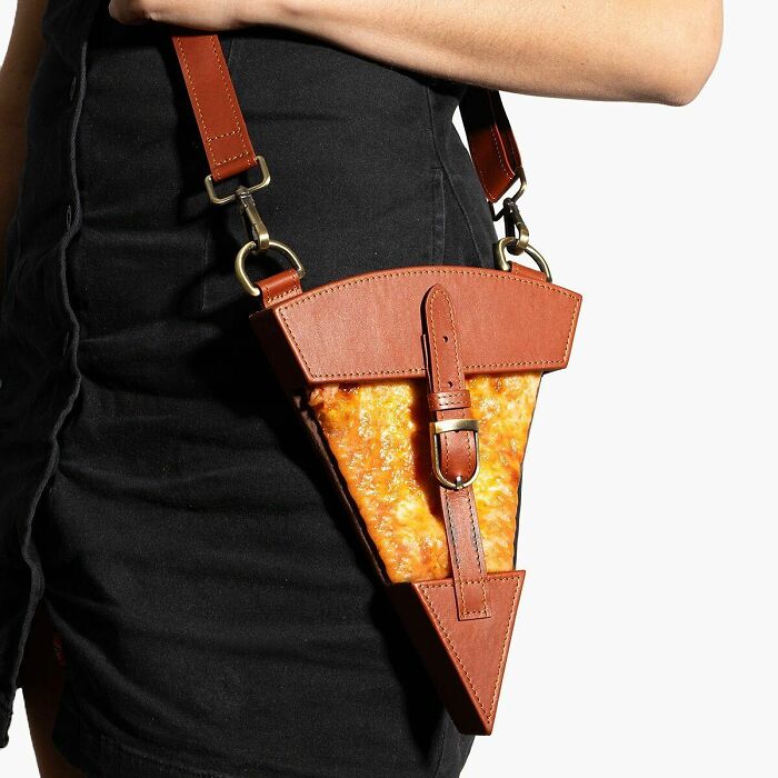 Unique fashion accessory by Nik Bentel shaped like a slice of pizza with brown leather details and strap.