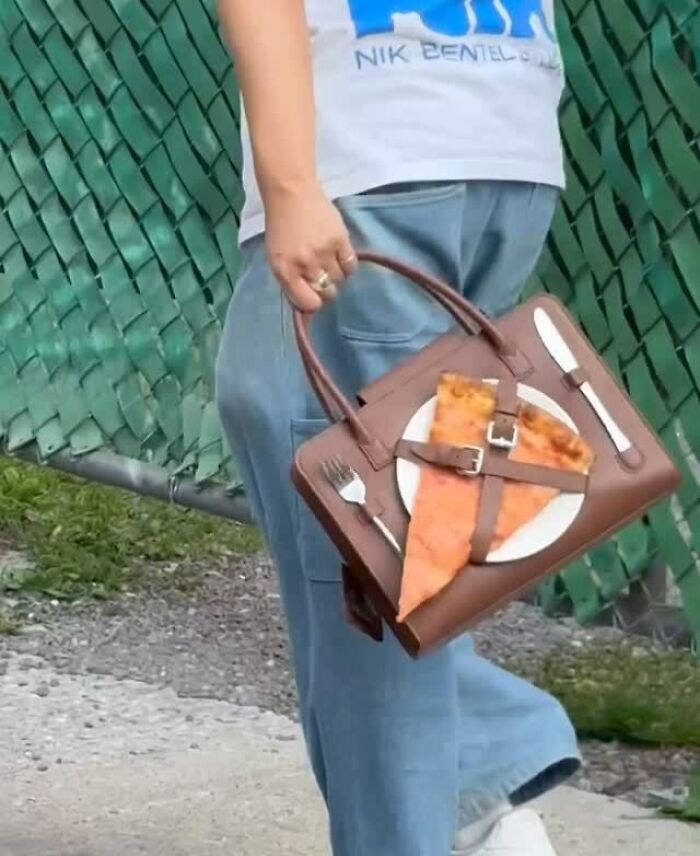 Person holding an unusual accessory handbag designed with pizza slice, plate, and cutlery elements blending everyday objects with fashion.