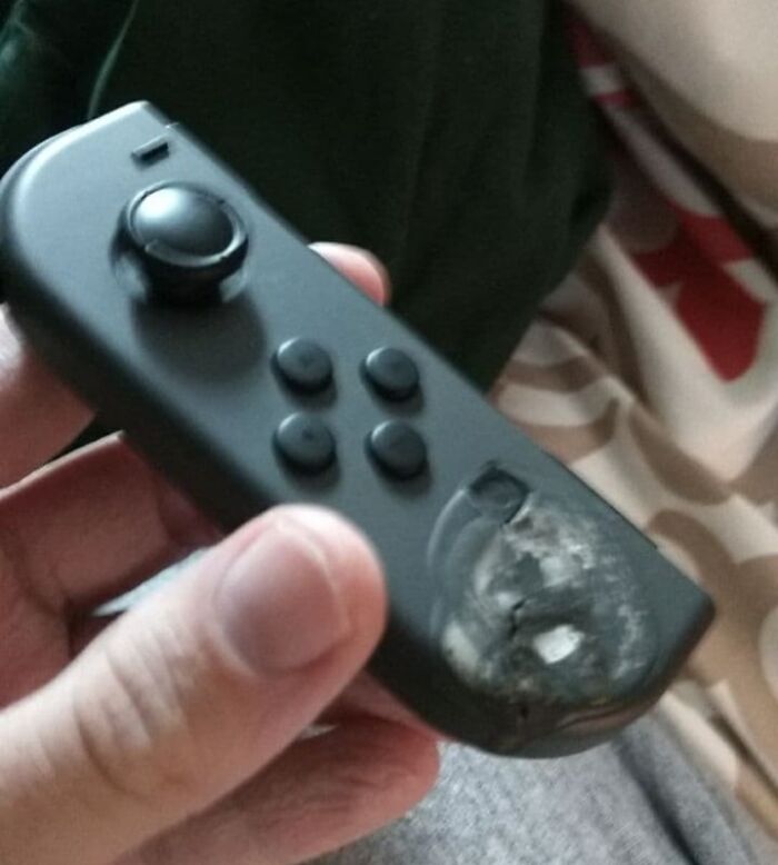 Hand holding a melted black game controller button damaged by this year's heatwaves causing a hot mess worldwide.