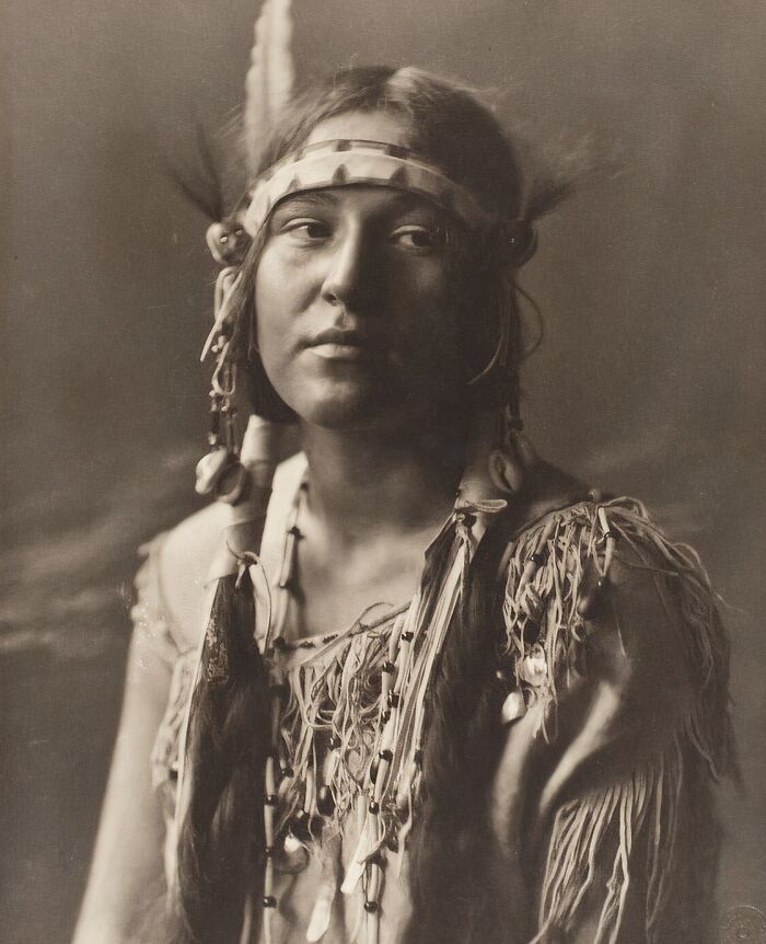 Native tribes member from the 1900s wearing traditional attire and feathers, captured to show the strength of native tribes.