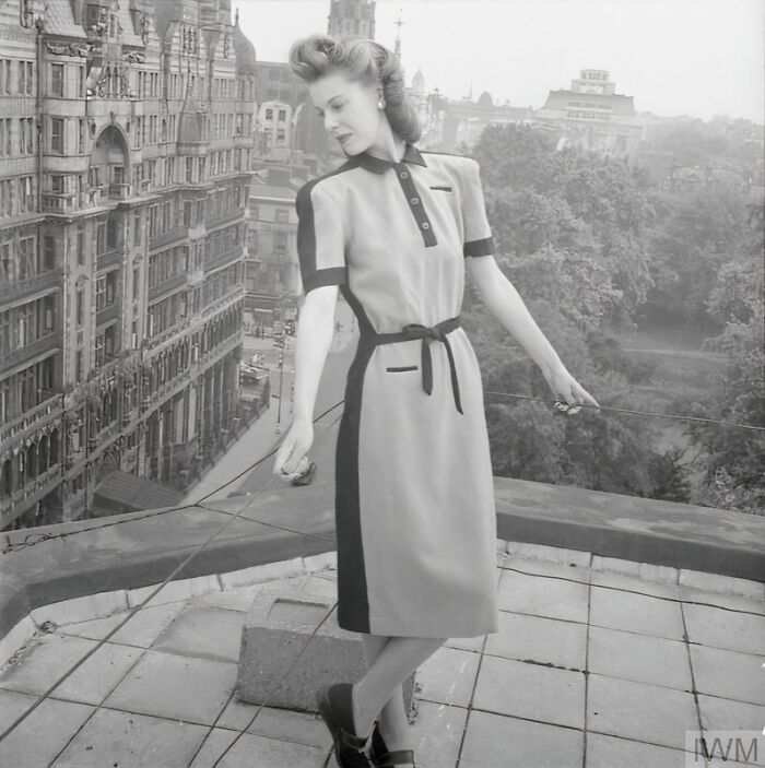 British woman in stylish WWII-era dress standing on rooftop, showcasing how British women kept their style during restrictions.