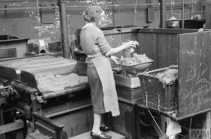 British woman working in a factory, demonstrating how British women kept their style during WWII restrictions.