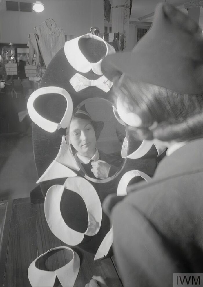 British woman trying on stylish collars and accessories during WWII reflecting how women kept their style amid restrictions.