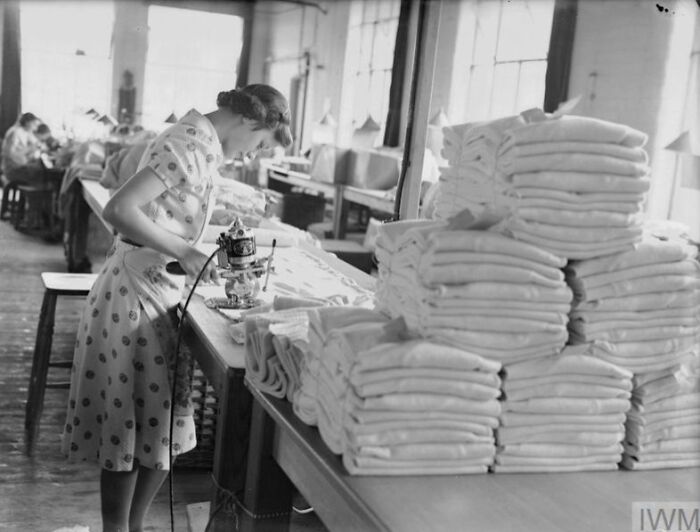 British woman sewing in a factory tailoring clothes, showcasing how British women kept their style during WWII restrictions.