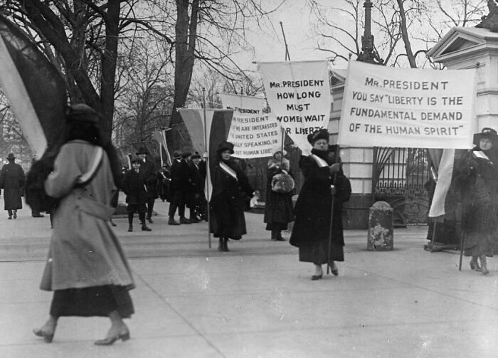 Women suffragists in the 20th century suffrage era protesting with signs demanding liberty and voting rights.
