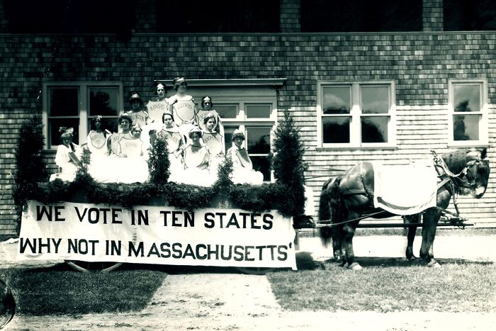 Women in the 20th century suffrage era on a decorated float advocating for voting rights in Massachusetts.