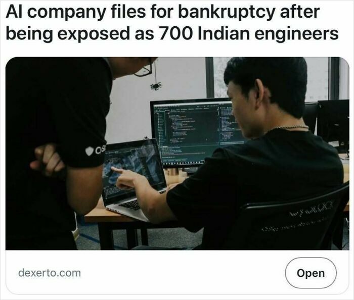 Two engineers reviewing code on multiple screens in an office, illustrating satire headlines that are unfortunately true.
