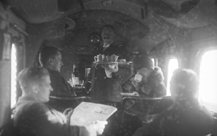 Passengers enjoying tea service inside a vintage airplane cabin, highlighting the glamour of early flying experiences.