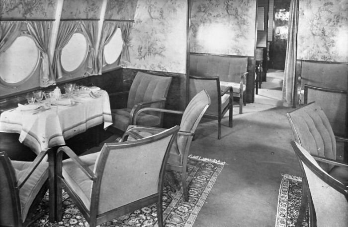 Vintage airplane interior featuring plush seating and elegant dining table, showcasing flying as an affair of pure glamour.