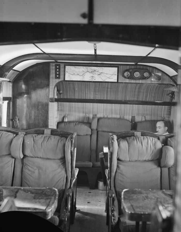 Vintage airplane cabin interior with cushioned seats and wood paneling, showcasing the glamour of early flying era.