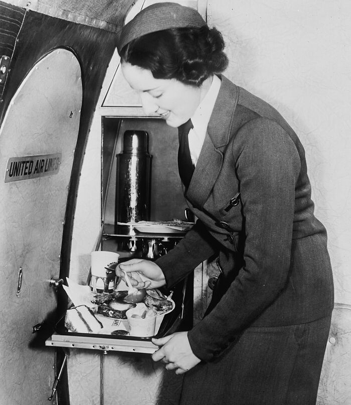 Vintage flight attendant serving a meal on United Airlines, showcasing the glamour of flying in the past.