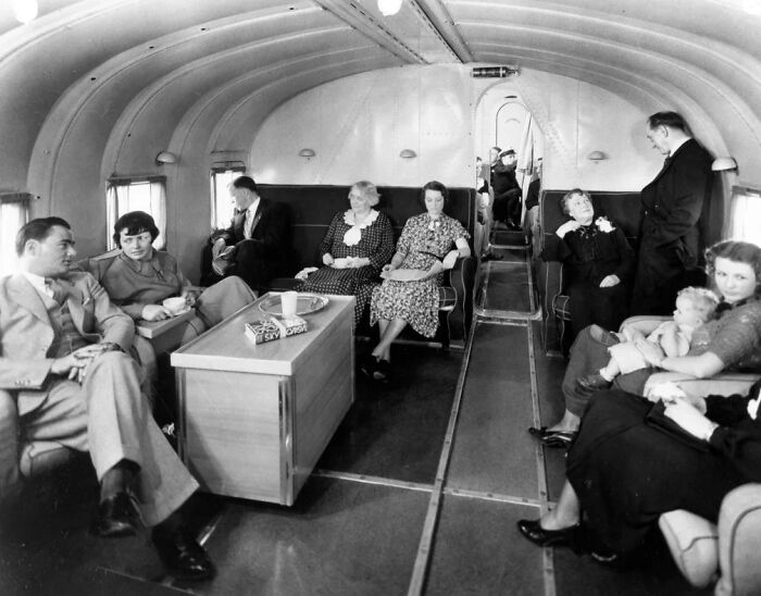 Vintage airplane interior showing passengers dressed elegantly, capturing the glamour of flying in the past.