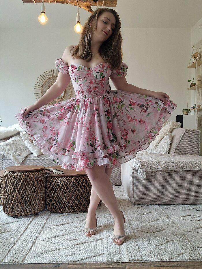 Woman wearing a handmade floral dress posing indoors, showcasing cool creative craftsmanship and design details.