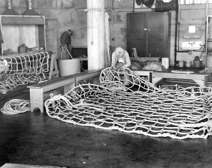 Prison labor at Alcatraz as an inmate works on large rope nets inside the facility workshop.