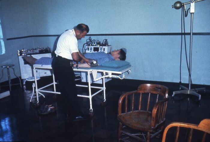 Medical exam of inmate on Alcatraz prison bed in a stark room, showing rare glimpses into the harsh reality of life on Alcatraz.