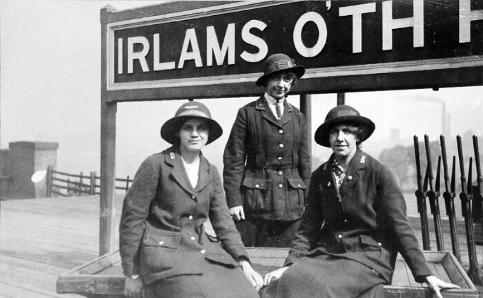 Three women in WWI uniforms posing at a train station, illustrating how women changed everything during WWI.