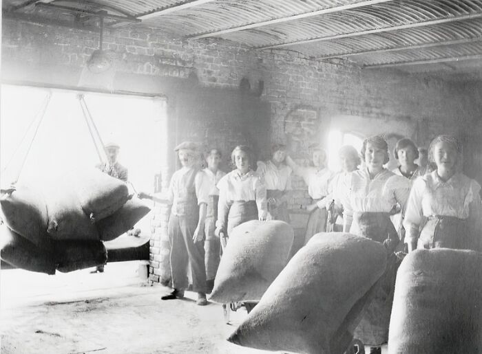 Women workers in a brick warehouse handling large sacks, demonstrating how women changed everything during WWI.