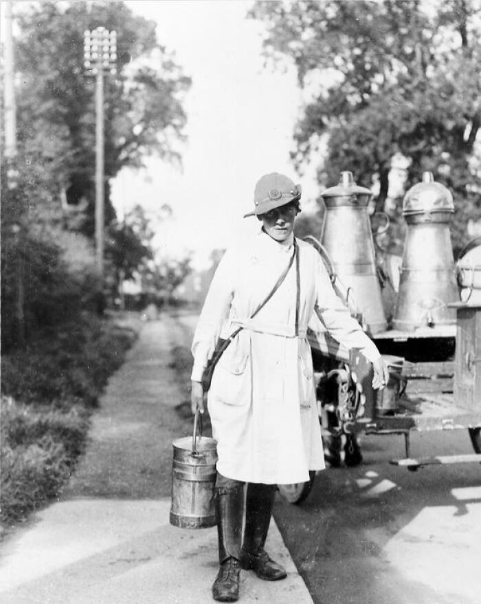 Woman in work uniform carrying metal containers outdoors representing women changing everything during WWI in history.