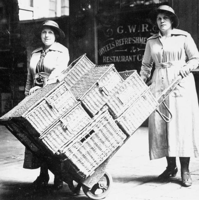 Two women in WWI-era attire handling wicker baskets on a large handcart, showing how women changed everything during WWI.