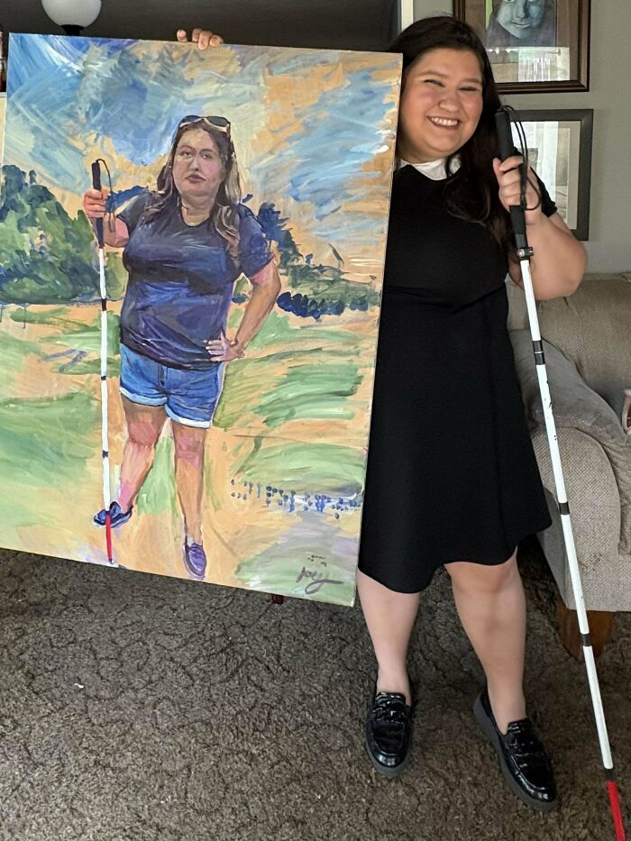 Woman holding a white cane poses next to a painted portrait of herself holding the same cane, showcasing cool creativity.