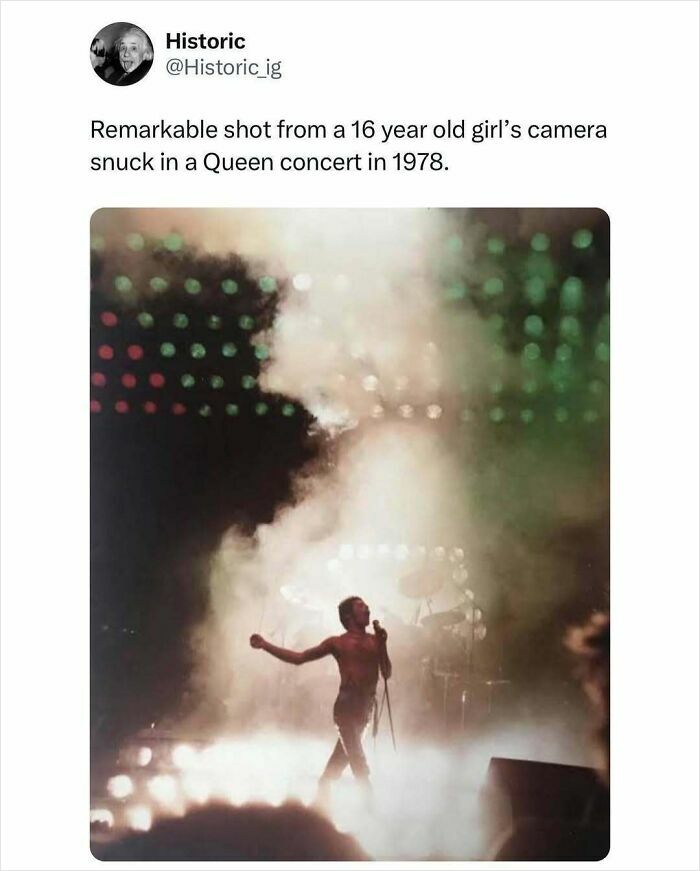 Historic photo of Queen concert from 1978 showing lead singer performing on a foggy, light-filled stage.