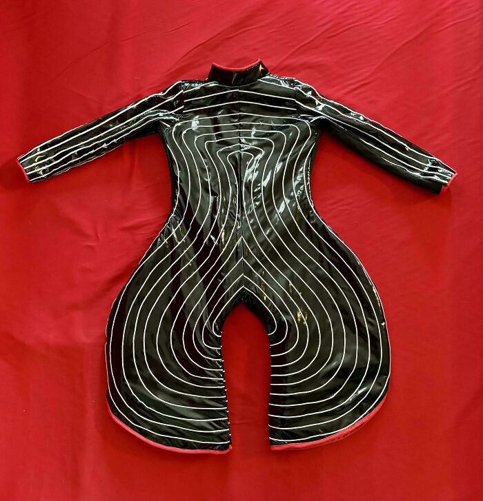 Black futuristic suit with white curved lines laid out on a red surface in a cool handmade design.