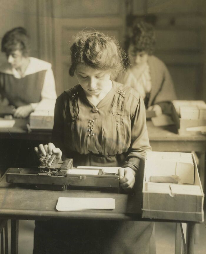 Young woman using a vintage machine, showing daily life beyond the WWI trenches in a historic indoor setting.