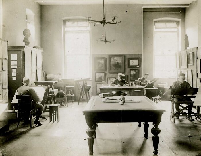 Soldiers in a WWI room working on drawings and tasks, revealing daily life beyond the WWI trenches.